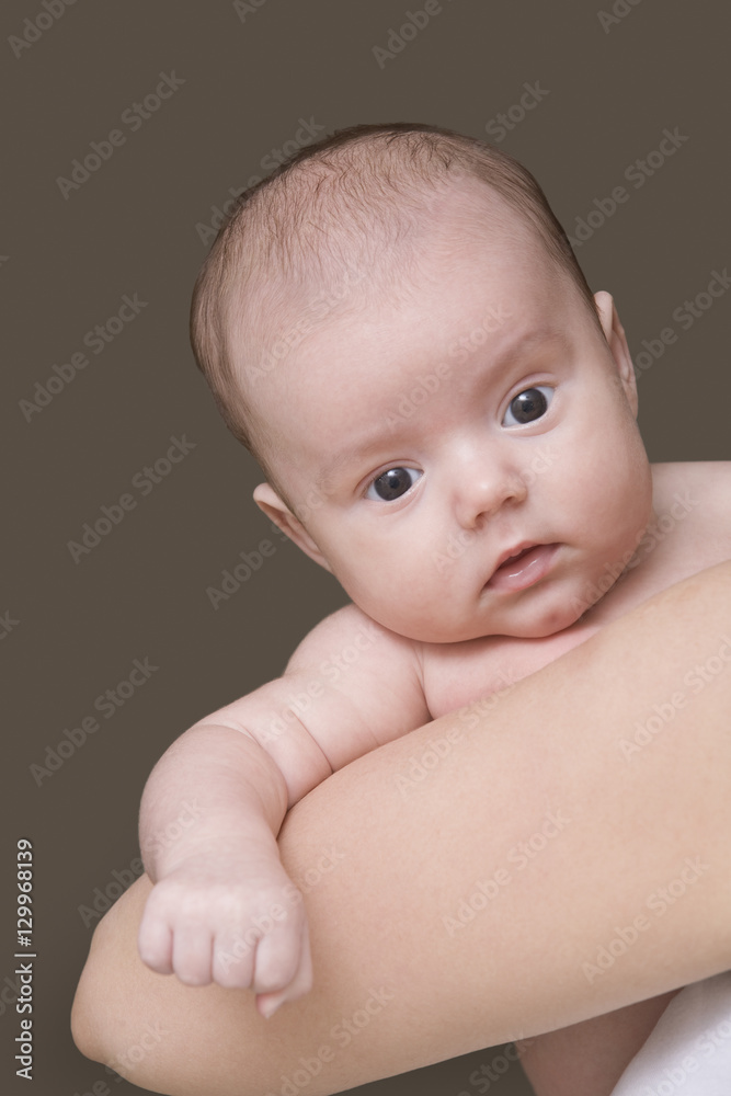 Closeup of a cropped mother carrying baby girl against gray background Closeup of a cropped mother carrying baby girl against gray background