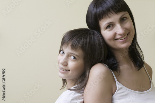 Portrait of a mother and daughter smiling against colored background