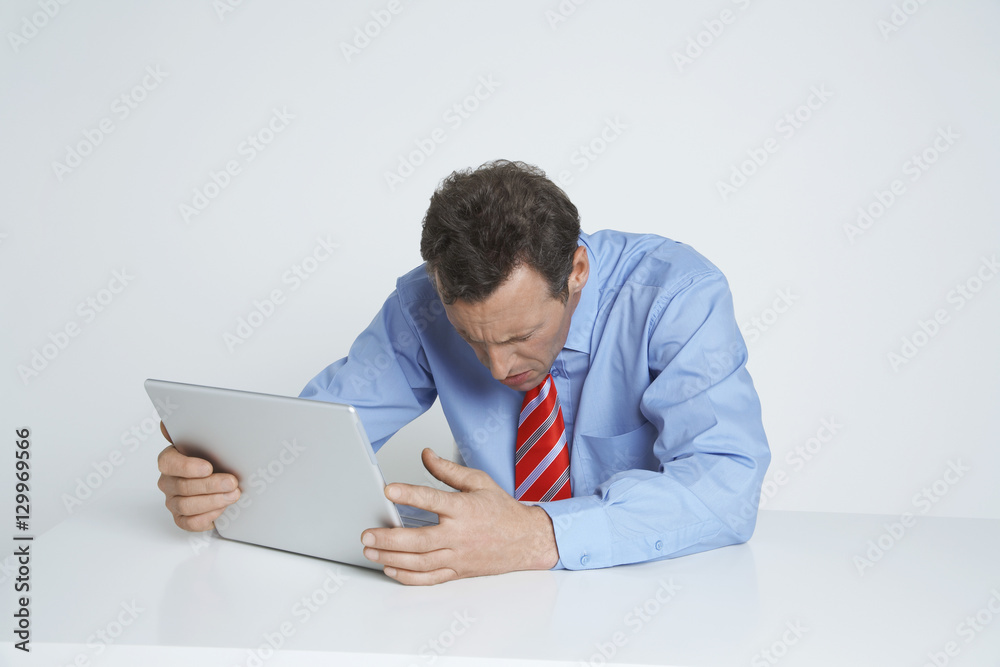 Depressed businessman with laptop at desk isolated over white background Depressed businessman with laptop at desk isolated over white background