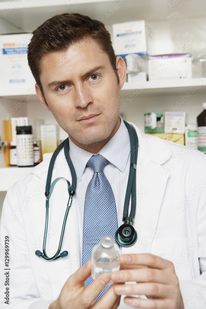 Portrait of a male doctor holding drug bottle in the clinic Portrait of a male doctor holding drug bottle in the clinic