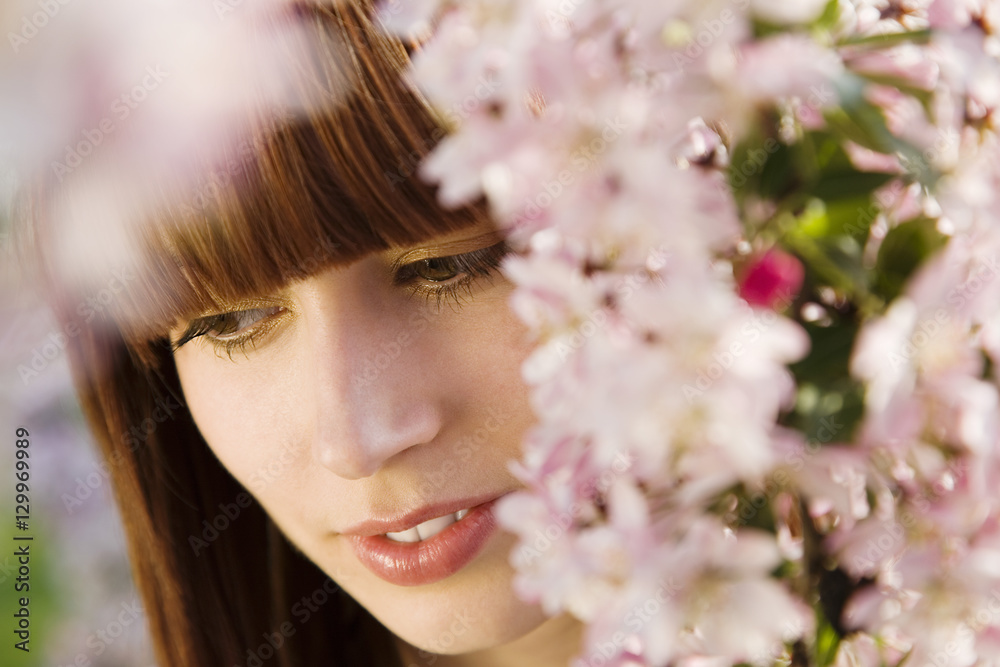 Closeup of attractive redhead woman under blossoming tree Closeup of attractive redhead woman under blossoming tree