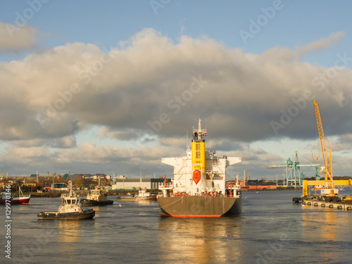 Tugboat assisting bulk cargo ship to leave port