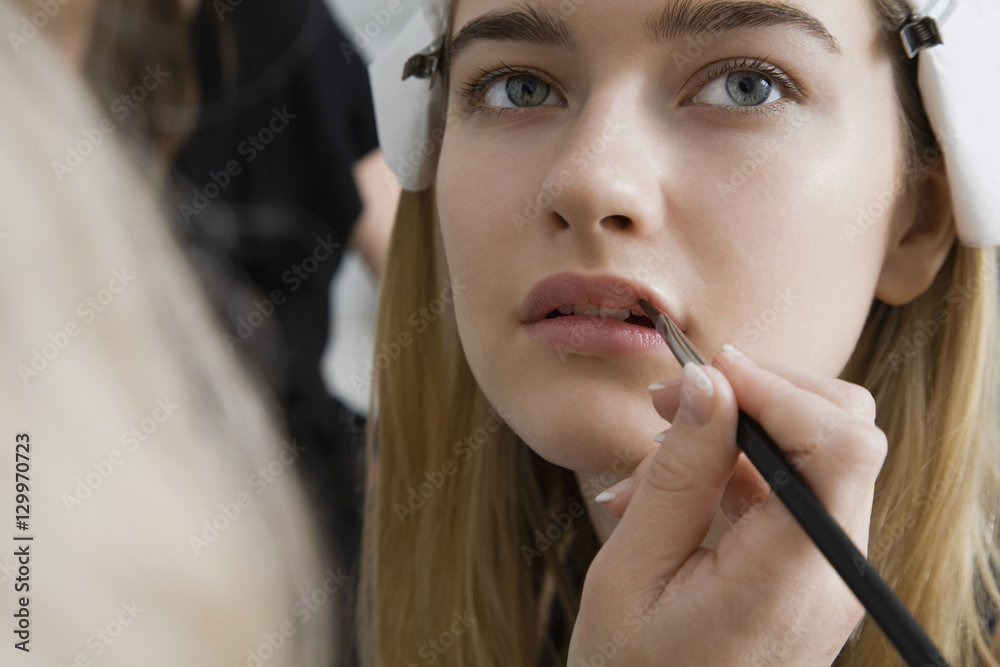 Closeup of a hand applying lipstick to female model's lips Closeup of a hand applying lipstick to female model's lips