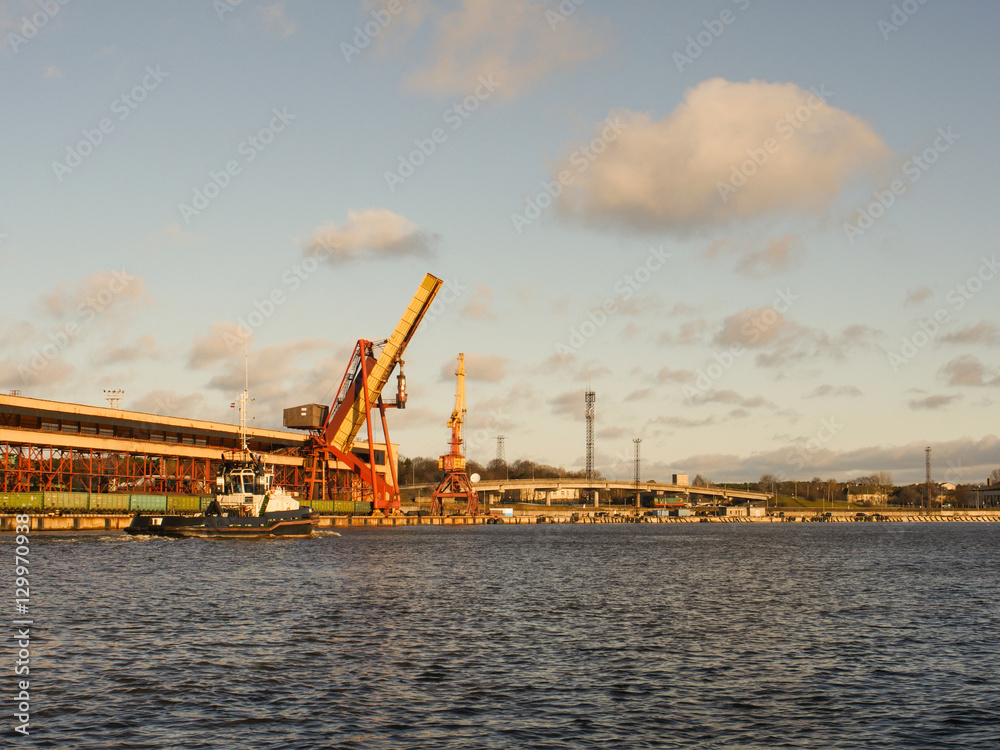 Fototapeta premium Tug vessel in the port, industrial background. Marine landscape