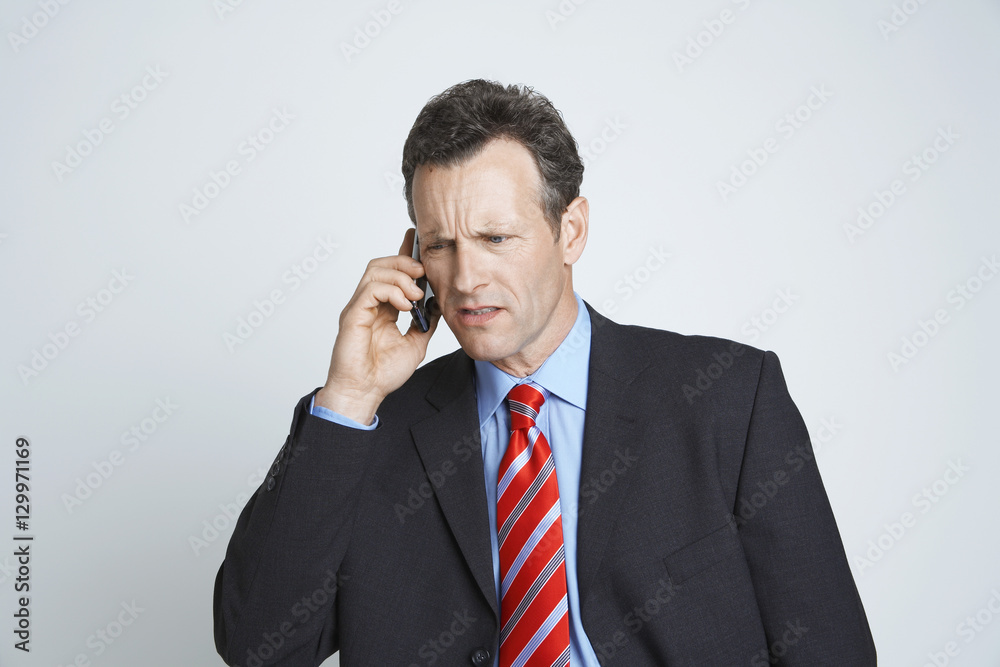 Tensed businessman communicating on cell phone isolated over white background Tensed businessman communicating on cell phone isolated over white background