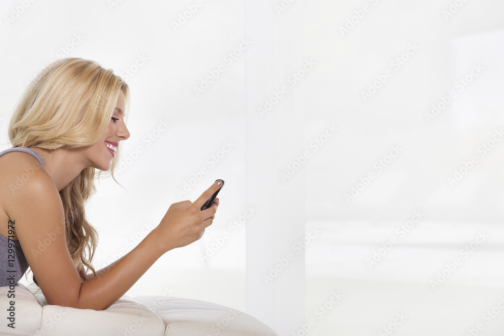 Side view of beautiful young woman reading text message on cell phone Side view of beautiful young woman reading text message on cell phone