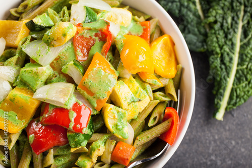 Close up of large white porcelain bowl of pasta and roasted vegetables with a creamy kale sauce