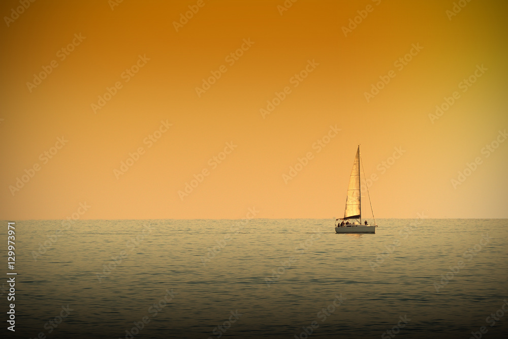 A boat navigating a tranquile sea at sunset time. Dark orange atmosphere. Empty copy space for Editor's text. A boat navigating a tranquile sea at sunset time. Dark orange atmosphere. Empty copy space for Editor's text.