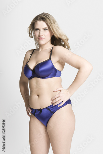 Sensuous young woman in sexy blue underwear against gray background