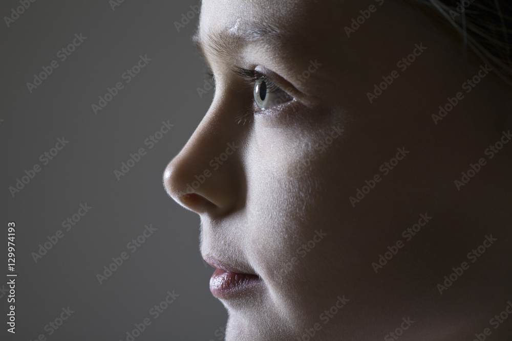 Closeup side view of a young girl against gray background