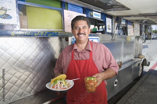 Vászonkép Portrait of happy man holding snack and refreshment outside a mobile cafe van