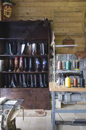Footwear on shelves by sewing machine at traditional shoemaker workshop