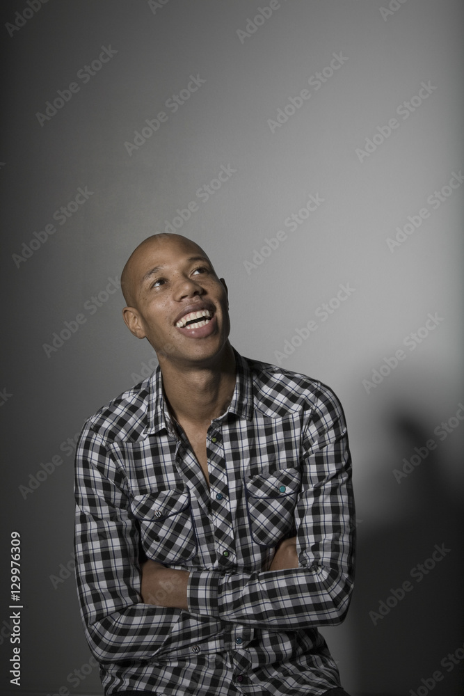 young African American man smiling while looking up against gray background young African American man smiling while looking up against gray background