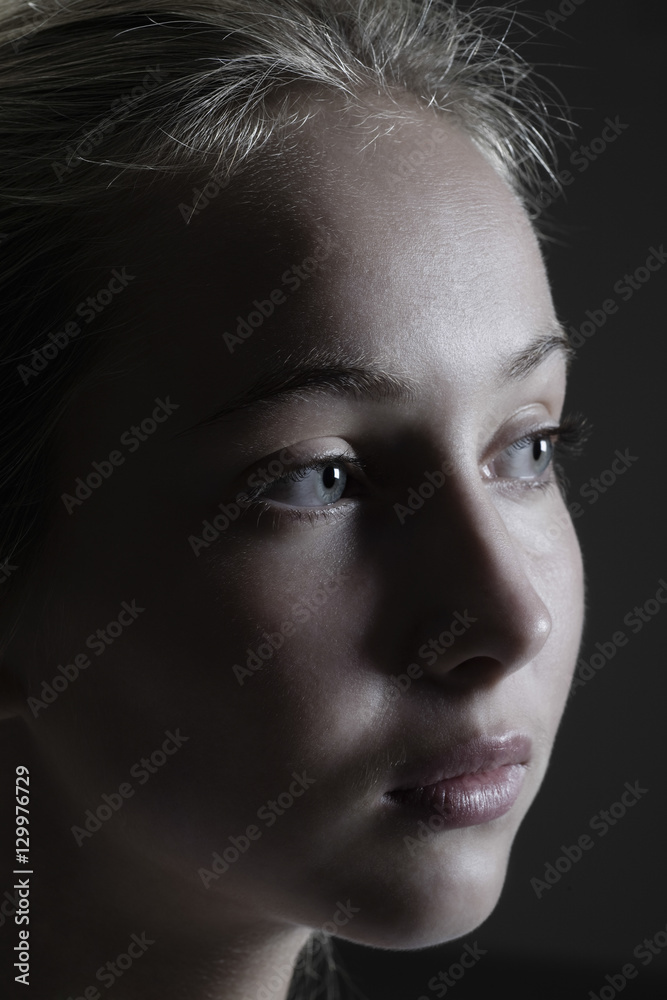 Fototapeta premium Closeup of a teenage girl looking away against black background