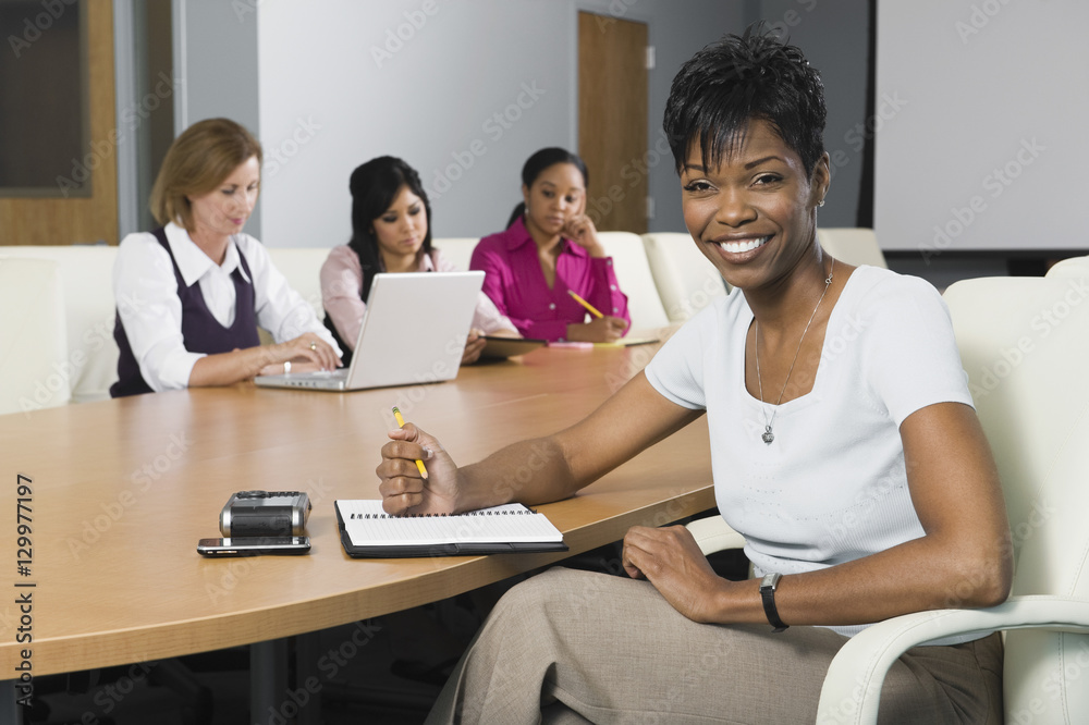 Portrait of a confident businesswoman with multiethnic colleagues in conference room