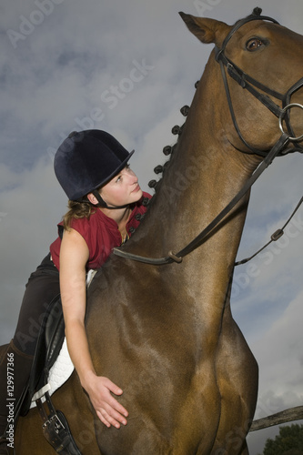Low angle view of a female horseback rider sitting on a brown horse