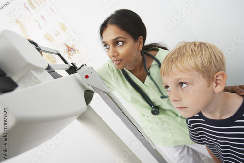 Boy and female doctor looking at the scale of weighing machine in the clinic