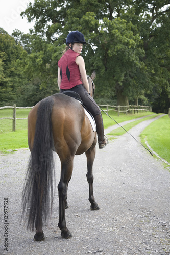 Full length portrait of a female horseback rider sitting on brown horse © moodboard