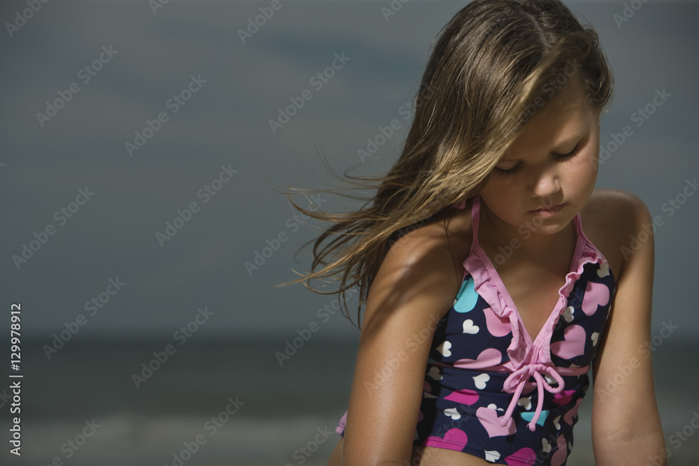 Sad little girl sitting at a beach