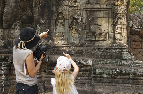 Rear view of mother and daughter pointing while looking at ancient temple