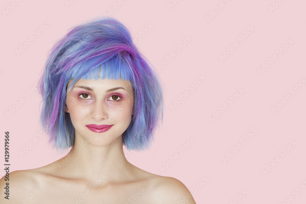Portrait of beautiful young woman with dyed hair against pink background