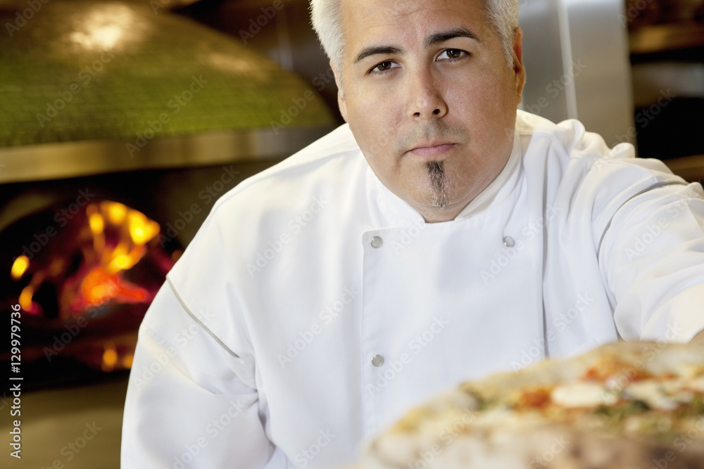 Close-up of a confident chef with pizza