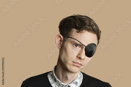 Slika na platnu Sad mid adult man wearing eye patch over colored background