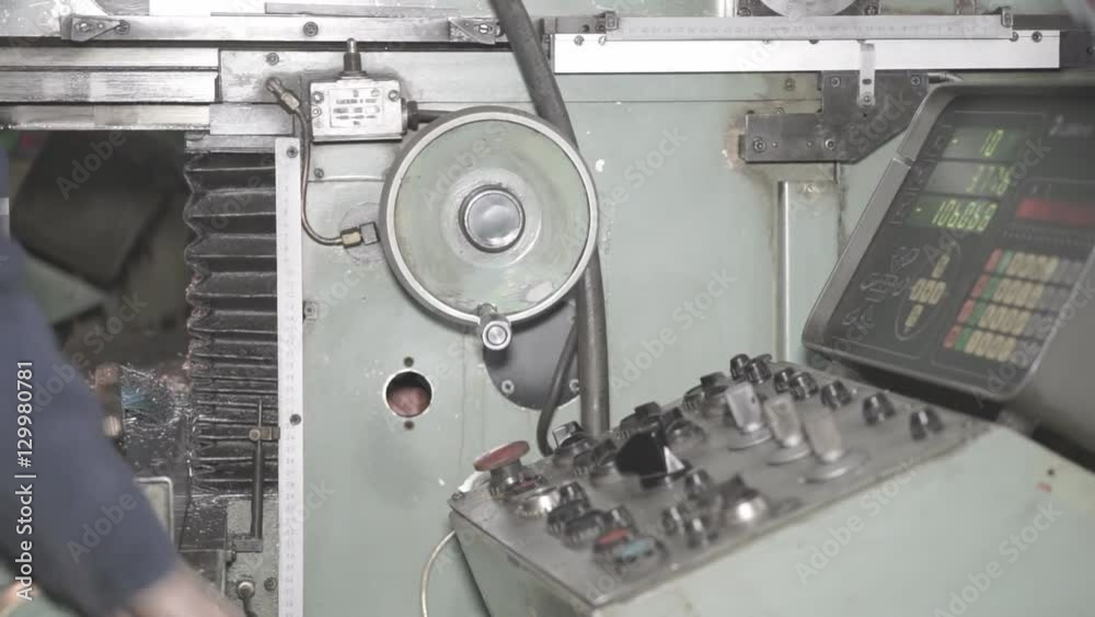 The Machine is Computer-Controlled Factory Worker is Setting Up CNC Lathe Machine in Factory. The Machine is Computer-Controlled Factory Worker is Setting Up CNC Lathe Machine in Factory.