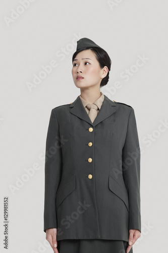 Female US military officer standing in attention as she looks away over gray background
