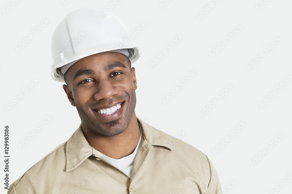 Portrait of happy African construction over with hardhat over gray background