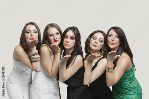 Five young women blowing kisses over gray background