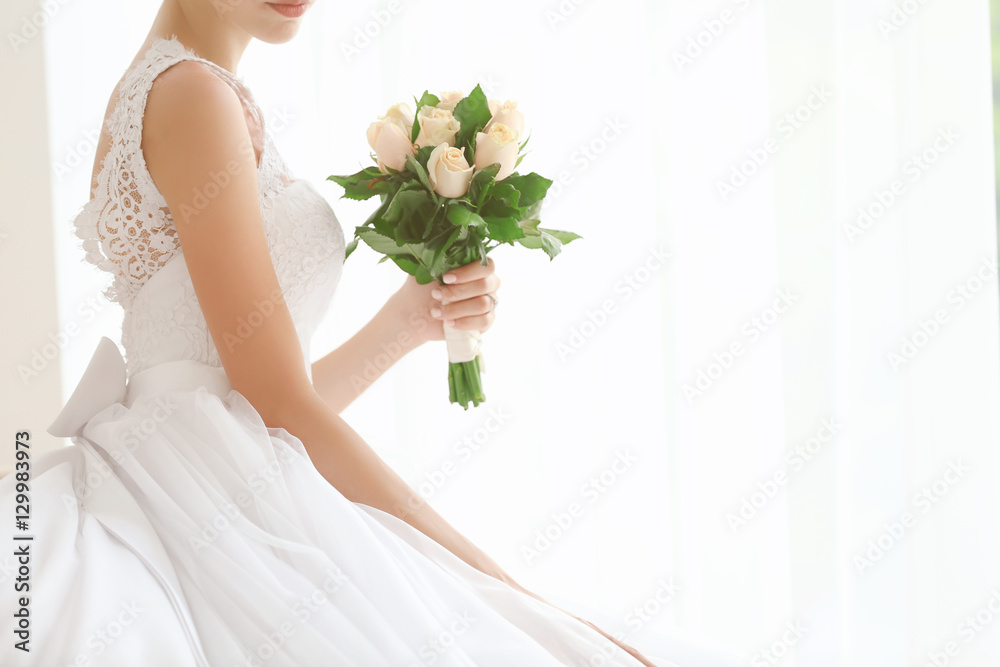 Bride in beautiful dress with wedding bouquet sitting on sofa Bride in beautiful dress with wedding bouquet sitting on sofa
