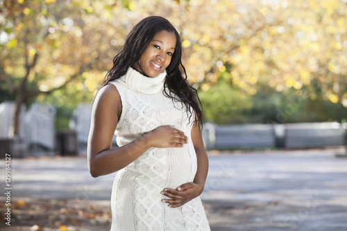 Portrait of happy young pregnant woman in park