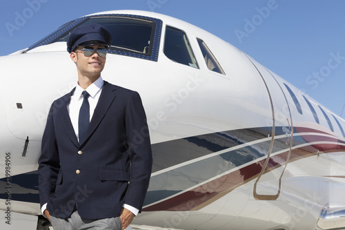 Handsome young pilot standing by private airplane