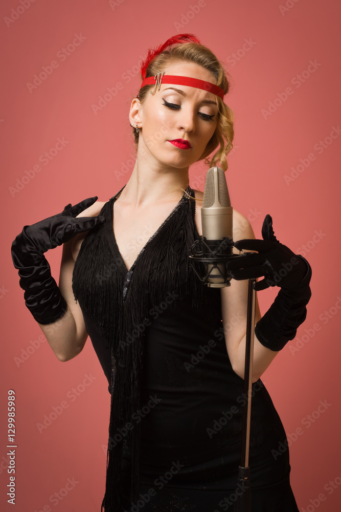 Pretty actress in black retro dress singing with microphone Pretty actress in black retro dress singing with microphone