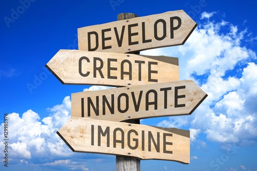 Wooden signpost with four arrows - develop, create, innovate, imagine. photo