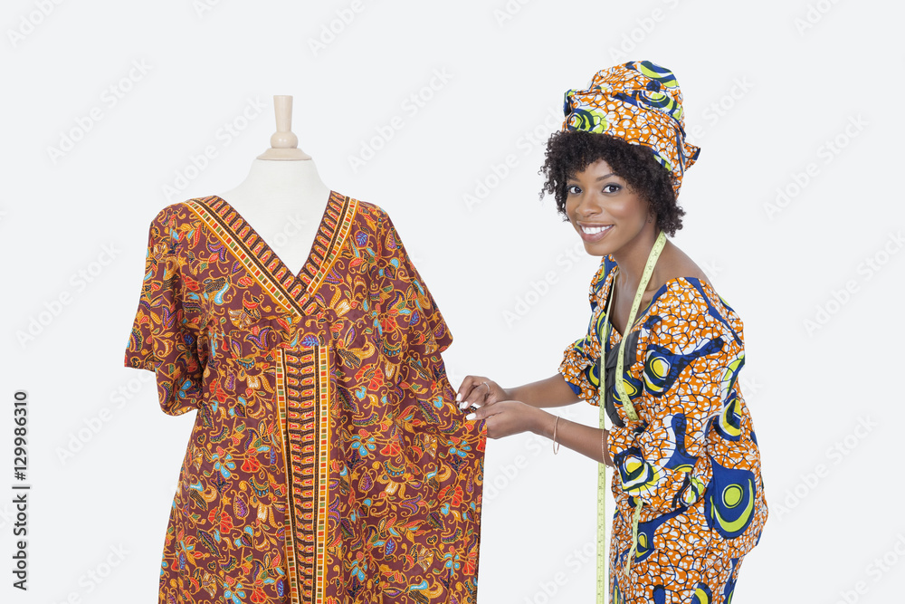Fototapeta premium Portrait of an African American female fashion designer working on dashiki over gray background