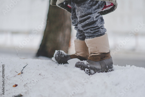 Ноги в сапогах на снегу зимой, маленький ребёнок