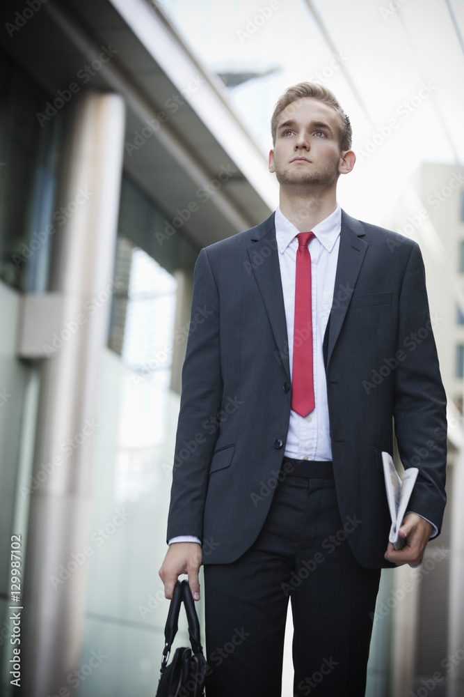 Young businessman in suit holding newspaper and bag Young businessman in suit holding newspaper and bag