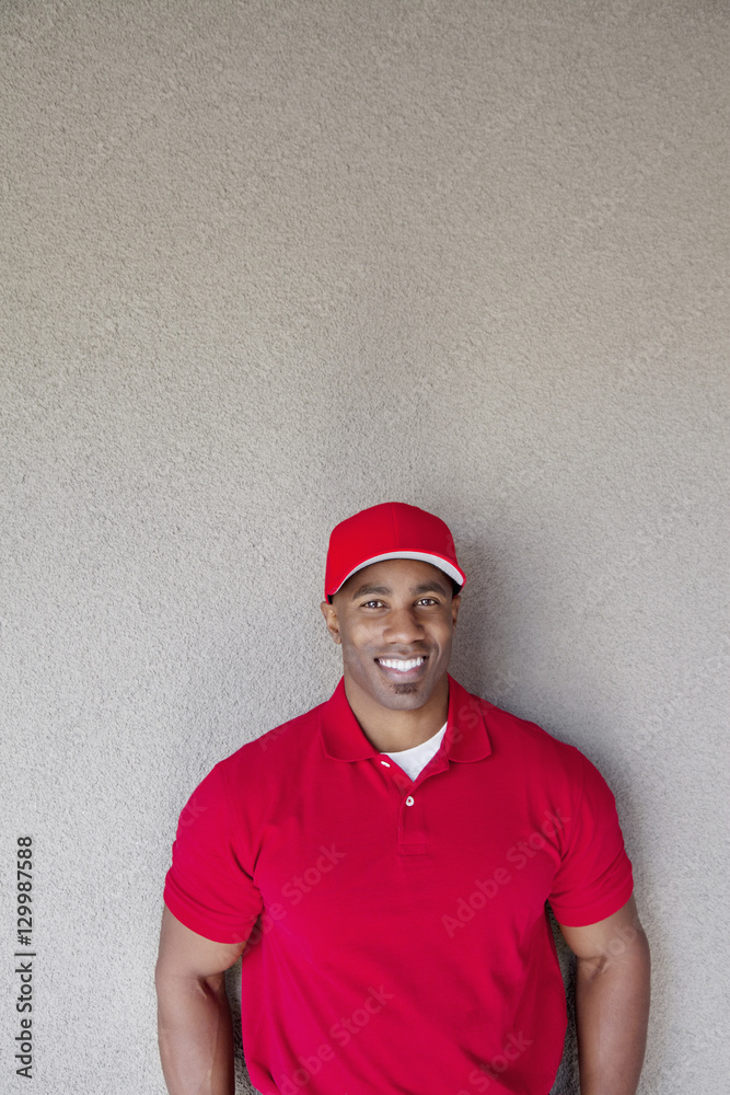 Portrait of a happy African American delivery man against wall