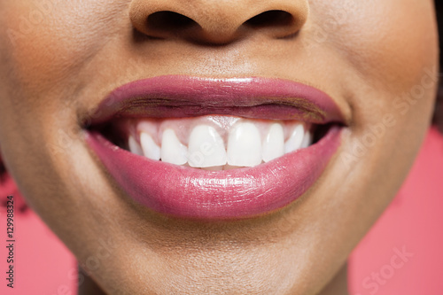 Close-up detail of an African American woman smiling over colored background