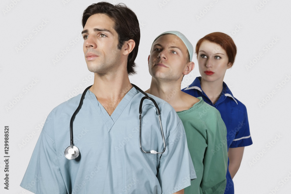 Medical practitioners standing together against gray background Medical practitioners standing together against gray background