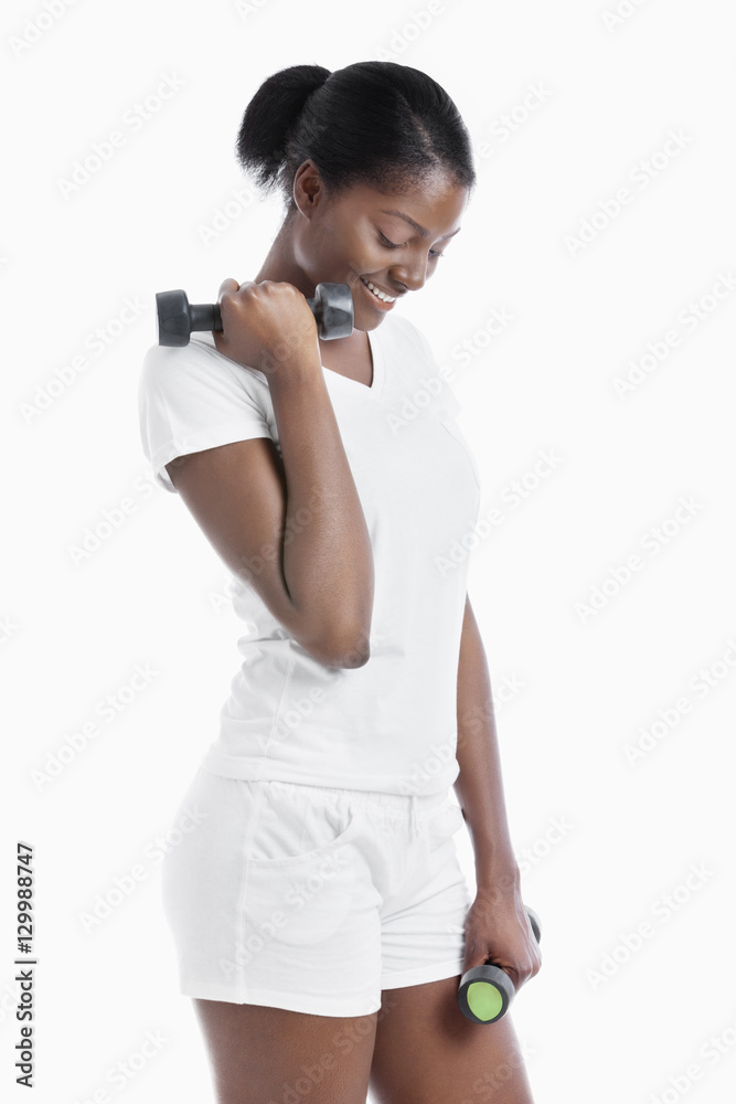 Thoughtful African American young woman with dumbbells standing over white background Thoughtful African American young woman with dumbbells standing over white background