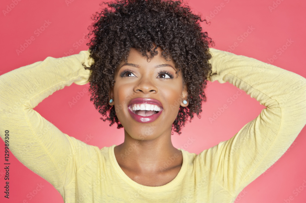 Cheerful African American looking up with hands behind head over colored background Cheerful African American looking up with hands behind head over colored background