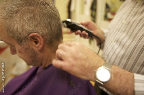 Midsection of senior barber giving haircut to customer in salon