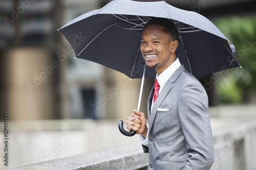 Happy African American businessman holding umbrella © moodboard