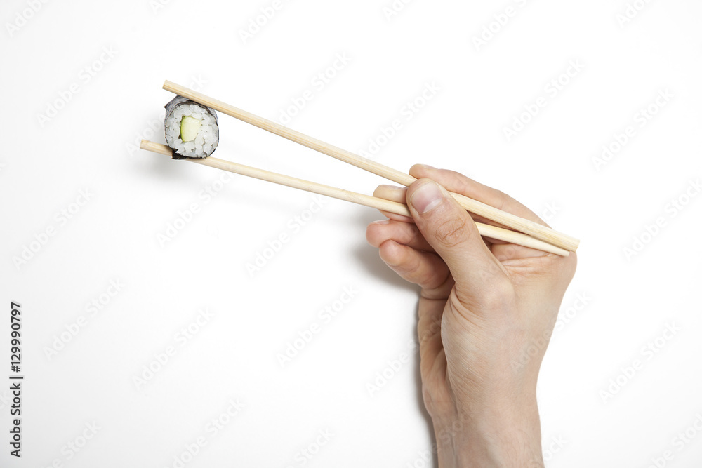 Man's hand holding sushi roll in chopsticks against white background Man's hand holding sushi roll in chopsticks against white background