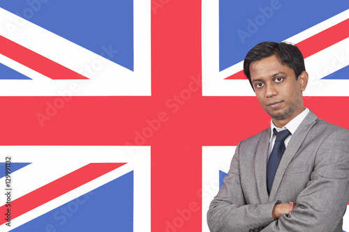 Portrait of young businessman with arms crossed over British flag