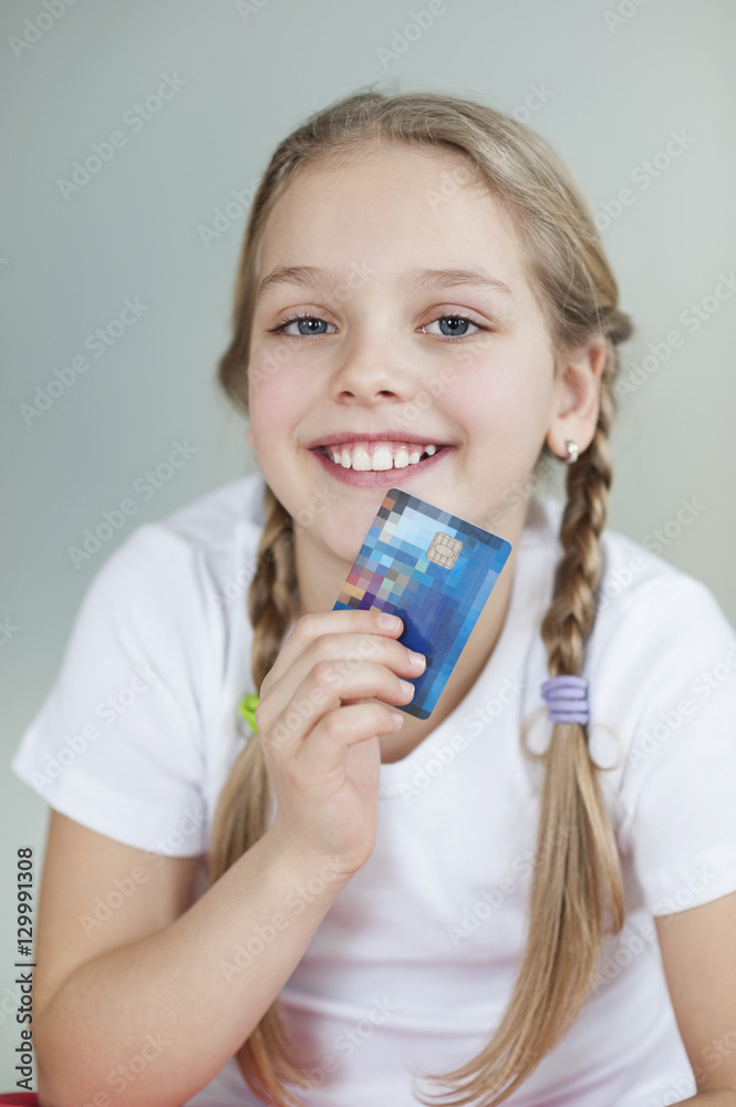 Portrait of a girl holding credit card over gray background Portrait of a girl holding credit card over gray background