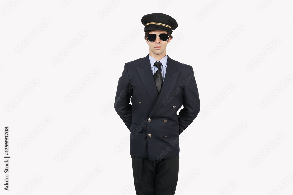 Young man in pilot uniform standing against gray background Young man in pilot uniform standing against gray background